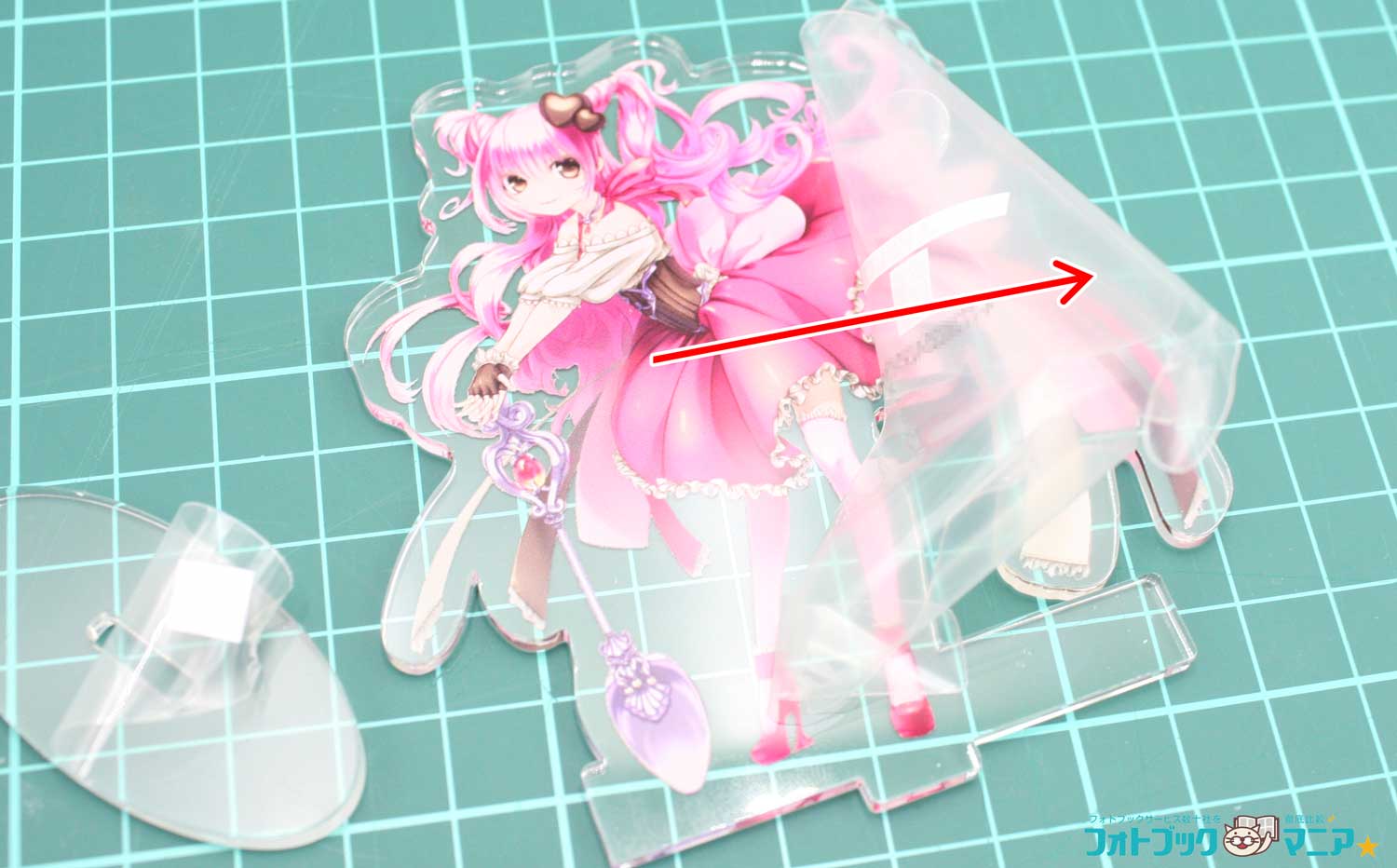 イラストのアクリルスタンドの保護フィルムを矢印の方向に剥がしている様子